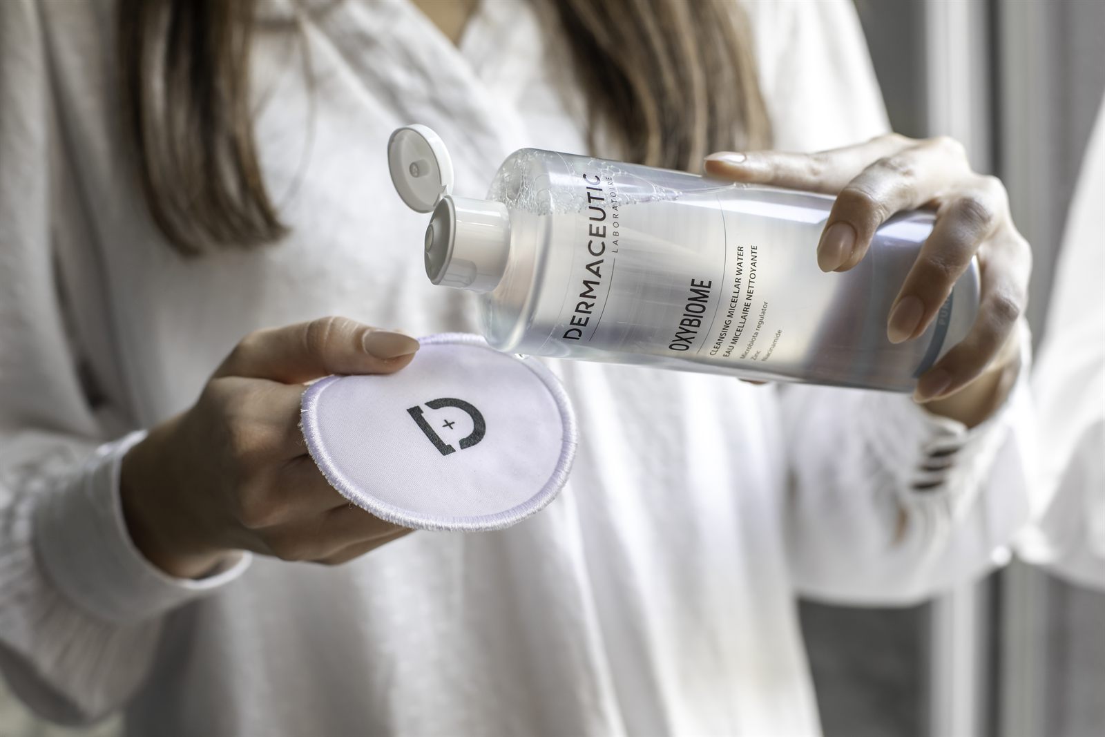 Micellair reinigingswater van Dermaceutic wordt op een herbruikbaar wattenpad gegoten
